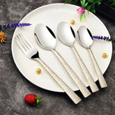 Elegant silver cutlery with engraved handles on a white plate, styled with flowers and berries.
